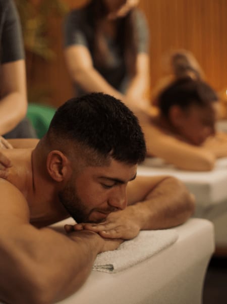 Nahaufnahme eines Mannes, der entspannt bei der Paarmassage liegt, im Hintergrund unscharf seine Partnerin